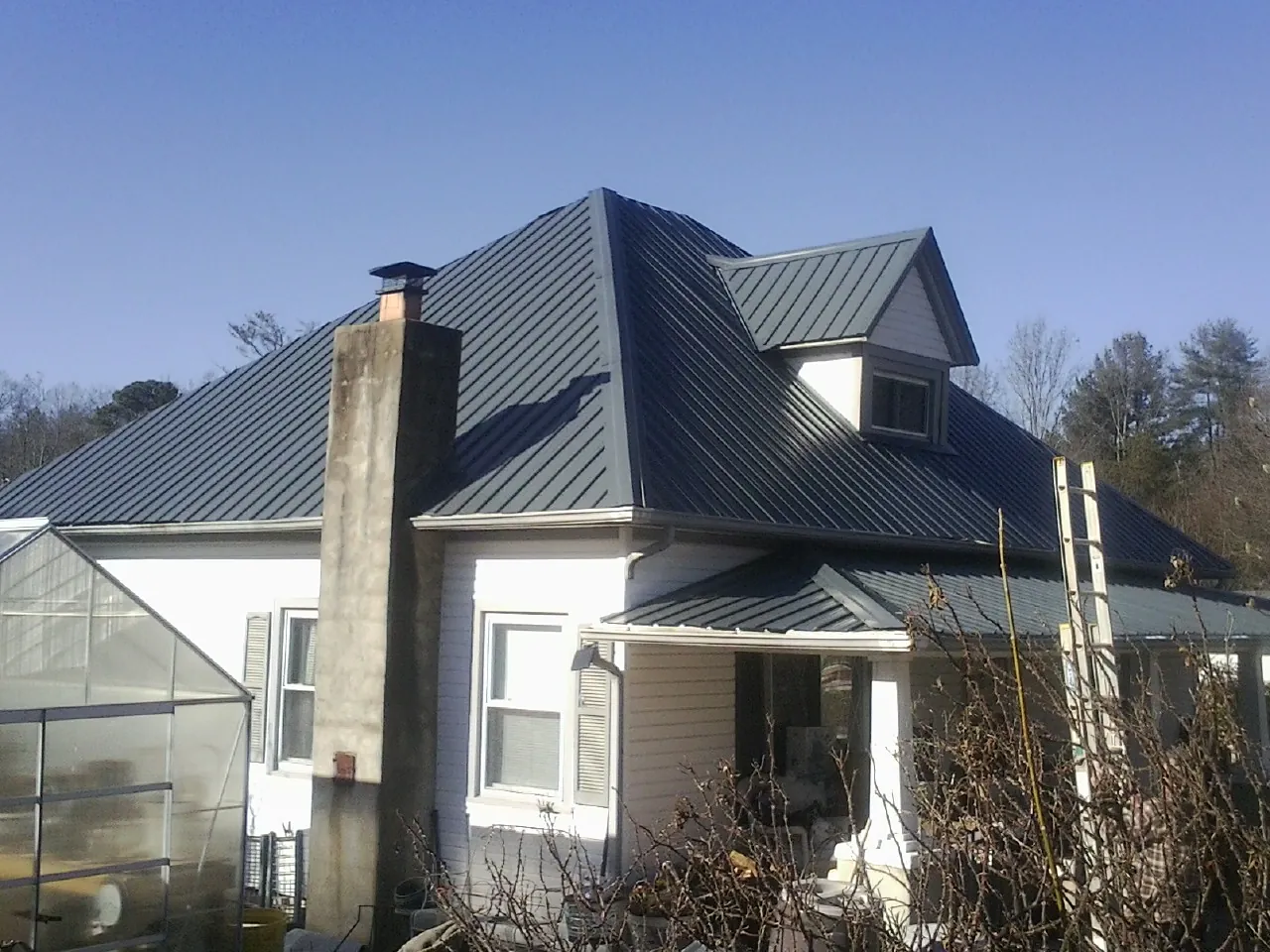 Dark blue standing seam metal roof on a white farmhouse with dormer — Slate & Tile Roof Repair by Roofing Brothers in Rock Falls