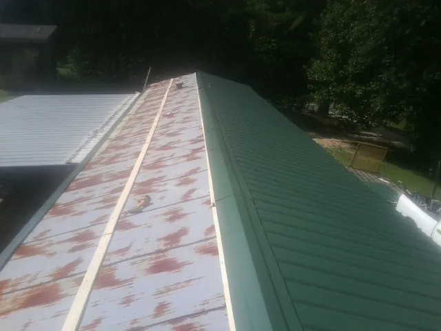Old rusted panels beside newly installed green metal roofing — Wind Damage Roof Repair by Roofing Brothers in Rock Falls
