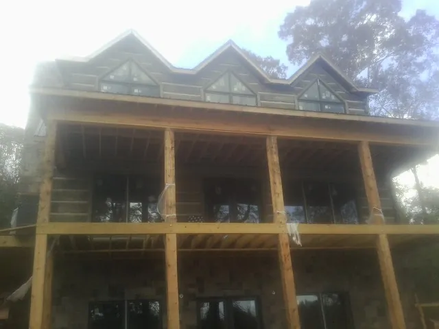 Dormers and porch framing on a large log home under construction — Roof Coating work by our crew in Rock Falls