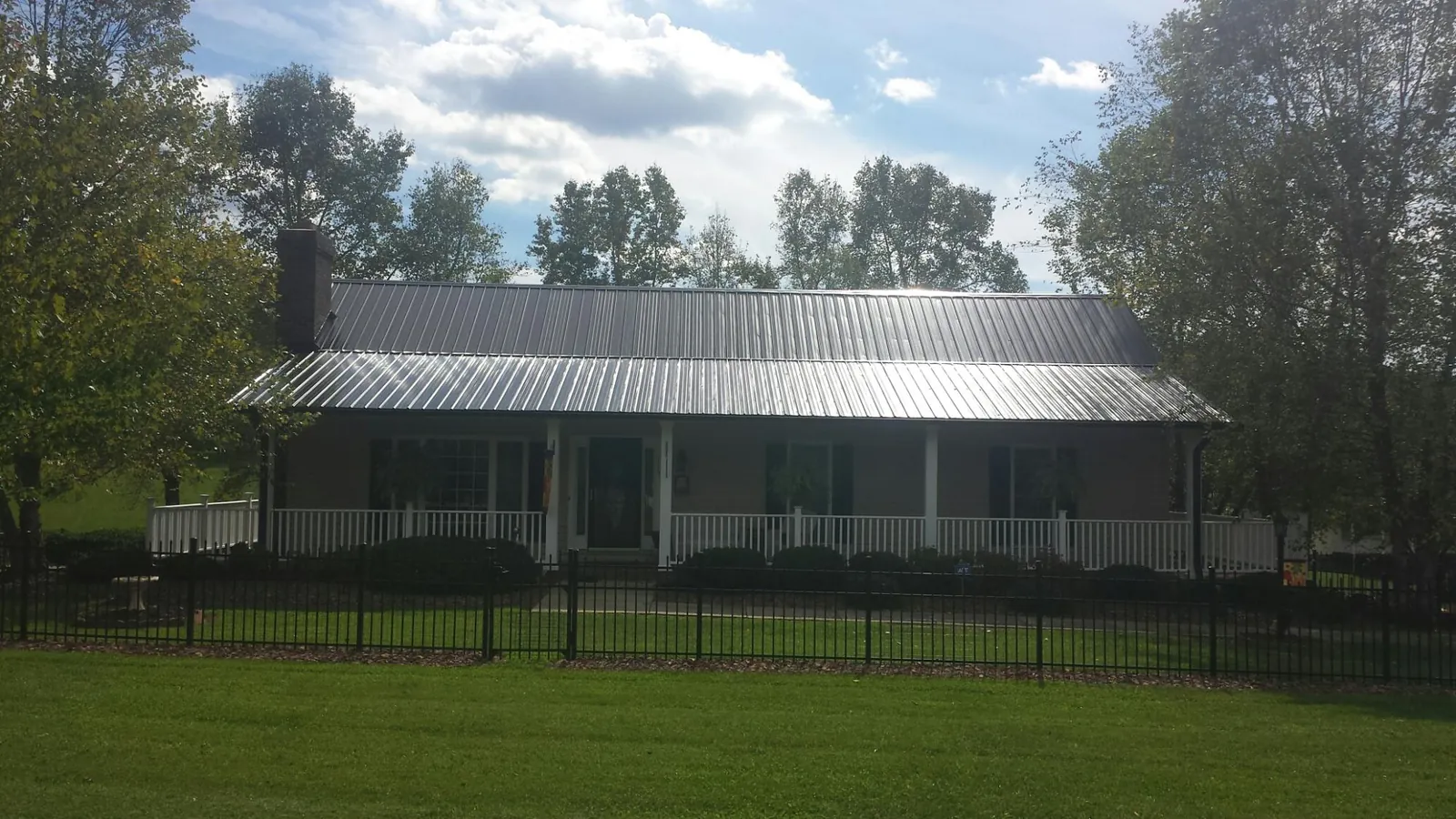 Gray metal roof on a brick ranch with a full width front porch — Gutter Guard Installation work by our crew in Rock Falls