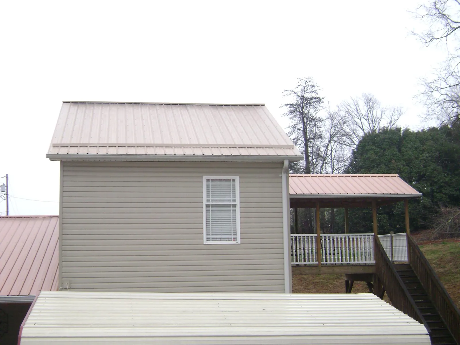 Tan metal roofs on a two story addition and attached porch, from a Roof Replacement job in Rock Falls